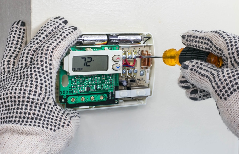 Furnace repairman installing digital thermostat